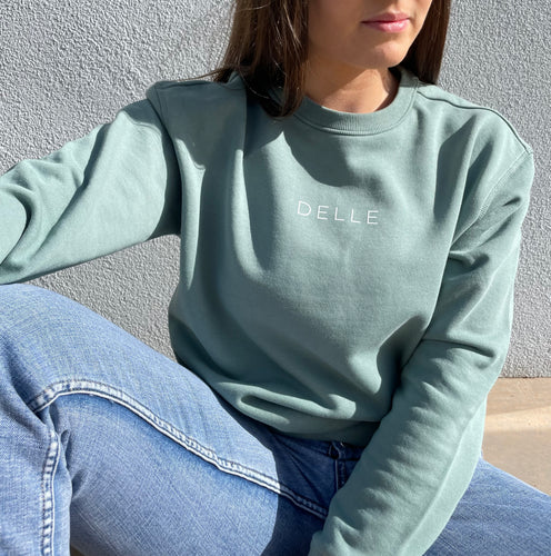 Sage green sweatshirt with white logo across chest